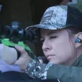 Femme concentrée visant avec un fusil de chasse, prête pour le bruit du tir.