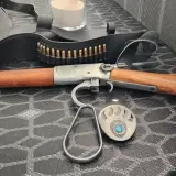 Carabine à levier sous garde en bois et métal, avec ceinture de munitions et boucle d'ours.