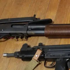 Un fusil à pompe riot gun et un pistolet-mitrailleur Uzi reposent sur un plancher en bois.