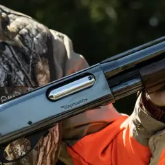 Un chasseur tient une arme Remington Wingmaster, un fusil de chasse classique, prêt pour l'action.