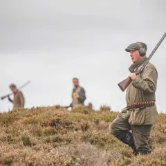 Chasseurs en tenue, fusils à l'épaule, dans un paysage de landes. L'interdiction du plomb tir sportif est une préoccupation croissante.