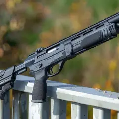 Un fusil tactique noir, avec une crosse réglable et une poignée ergonomique, posé sur une rambarde. C'est peut-être son premier fusil.