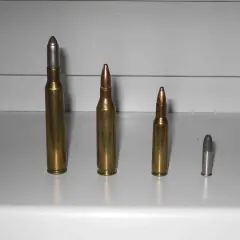 Comparaison de munitions : une cartouche 222 Remington à gauche, une 223 Remington au centre, et deux plus petites à droite.