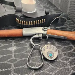 Carabine à levier sous garde en bois et métal, avec ceinture de munitions et boucle d'ours.