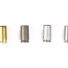 Quatre douilles de balle de différents matériaux : laiton, acier gris, acier argenté et acier brossé.