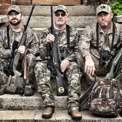 Trois chasseurs en tenue de camouflage, prêts pour traquer le cerf avec leurs fusils, dont un calibre 30 06.