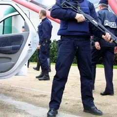 Un policier national tient un fusil à pompe, prêt à intervenir.