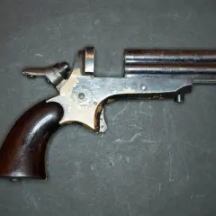 Un vieux derringer 22lr à double canon, avec une poignée en bois sombre et un mécanisme visible.