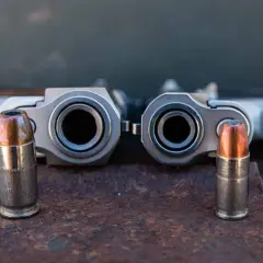 Deux canons de pistolets, un calibre 45 et un 9mm, se font face, chacun flanqué d'une balle.