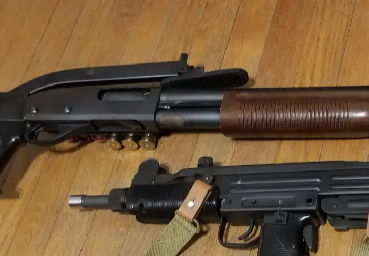 Un fusil à pompe riot gun et un pistolet-mitrailleur Uzi reposent sur un plancher en bois.