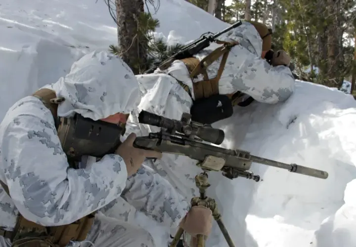 Deux snipers américains en tenue de camouflage hivernal se positionnent dans la neige, l'un visant avec son fusil sniper américain.