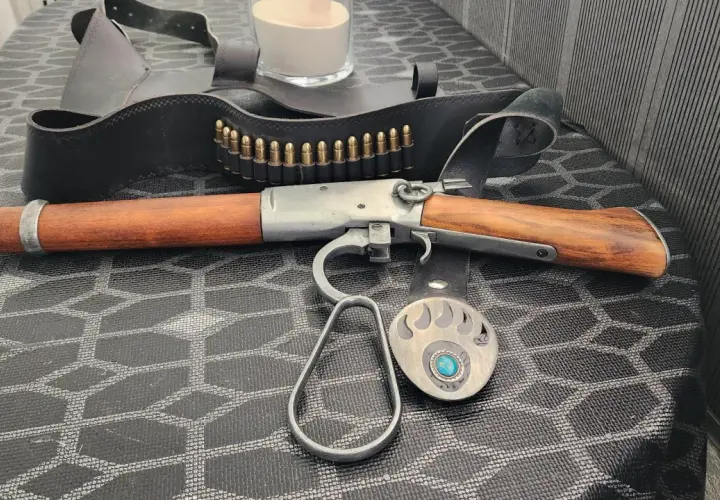 Carabine à levier sous garde en bois et métal, avec ceinture de munitions et boucle d'ours.