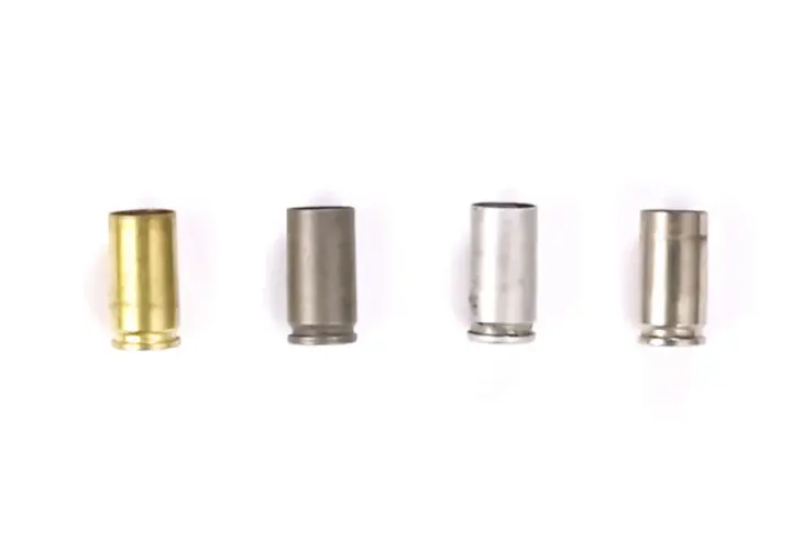 Quatre douilles de balle de différents matériaux : laiton, acier gris, acier argenté et acier brossé.