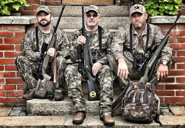 Trois chasseurs en tenue de camouflage, prêts pour traquer le cerf avec leurs fusils, dont un calibre 30 06.