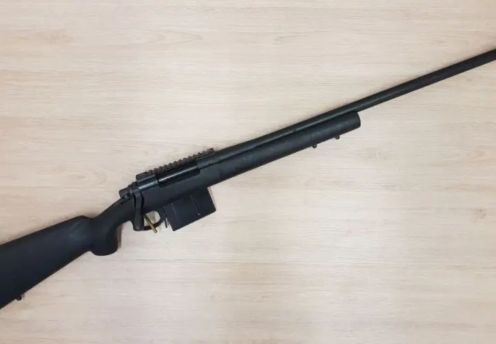Fusil noir Remington 700 Police, prêt pour l'action sur fond de bois clair.
