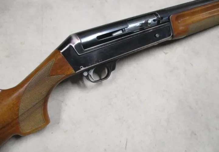 Le fusil de chasse Benelli 121, avec sa crosse en bois et son mécanisme apparent, prêt pour l'action.