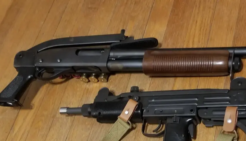 Un fusil à pompe riot gun et un pistolet-mitrailleur Uzi reposent sur un plancher en bois.