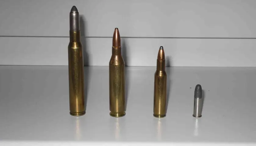 Comparaison de munitions : une cartouche 222 Remington à gauche, une 223 Remington au centre, et deux plus petites à droite.