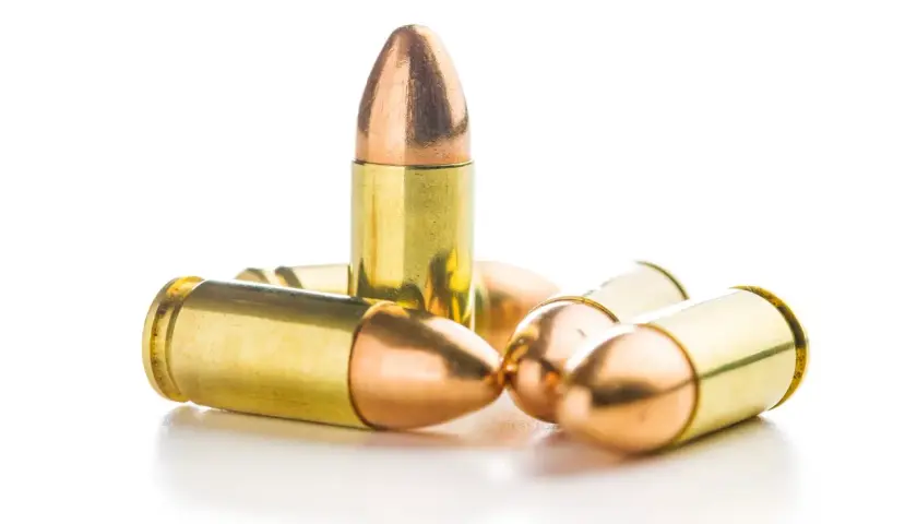 Un groupe de balles 9mm rip, leurs douilles dorées et leurs pointes cuivrées brillent sur fond blanc.