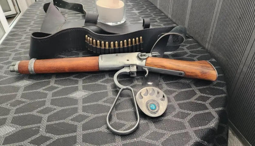 Carabine à levier sous garde en bois et métal, avec ceinture de munitions et boucle d'ours.