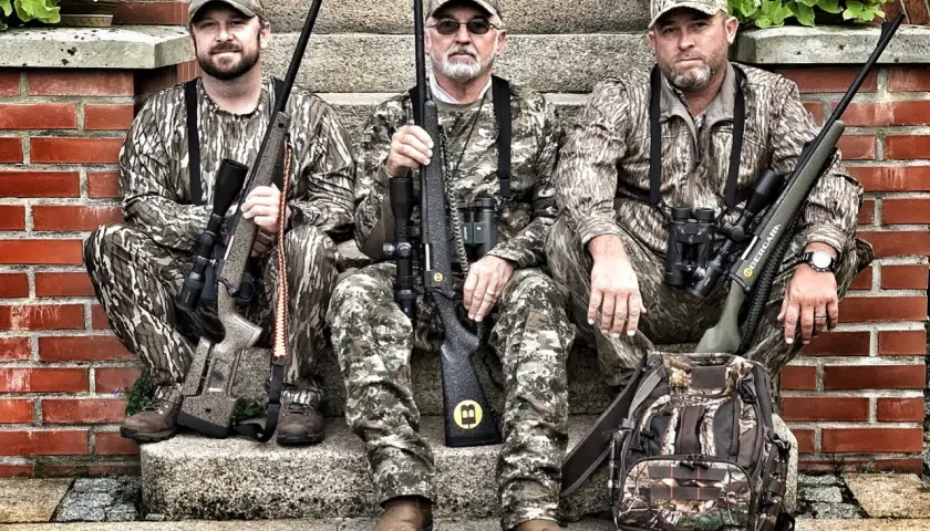 Trois chasseurs en tenue de camouflage, prêts pour traquer le cerf avec leurs fusils, dont un calibre 30 06.