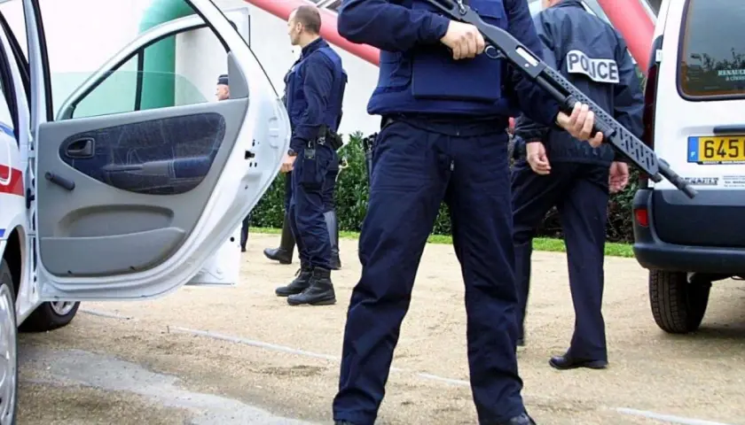 Un policier national tient un fusil à pompe, prêt à intervenir.