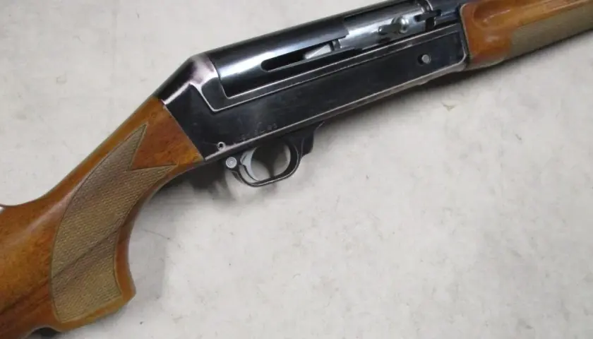Le fusil de chasse Benelli 121, avec sa crosse en bois et son mécanisme apparent, prêt pour l'action.