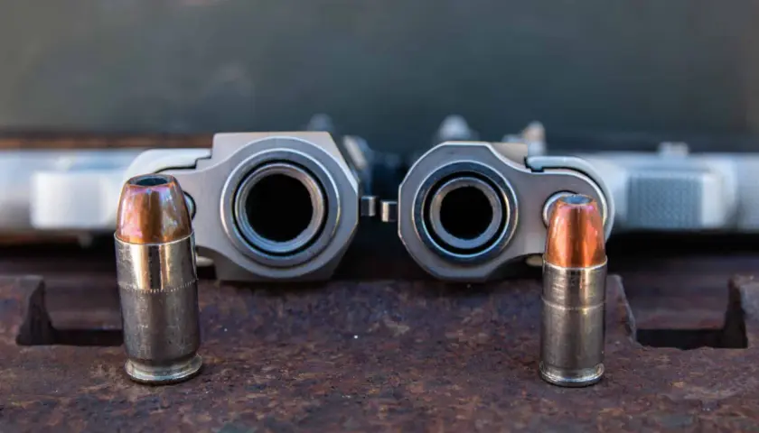 Deux canons de pistolets, un calibre 45 et un 9mm, se font face, chacun flanqué d'une balle.