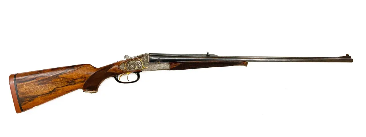 Carabine de chasse à double canon, ornée de gravures fines. Son bois veiné et sa conception suggèrent la carabine de chasse la plus puissante pour les grands gibiers.