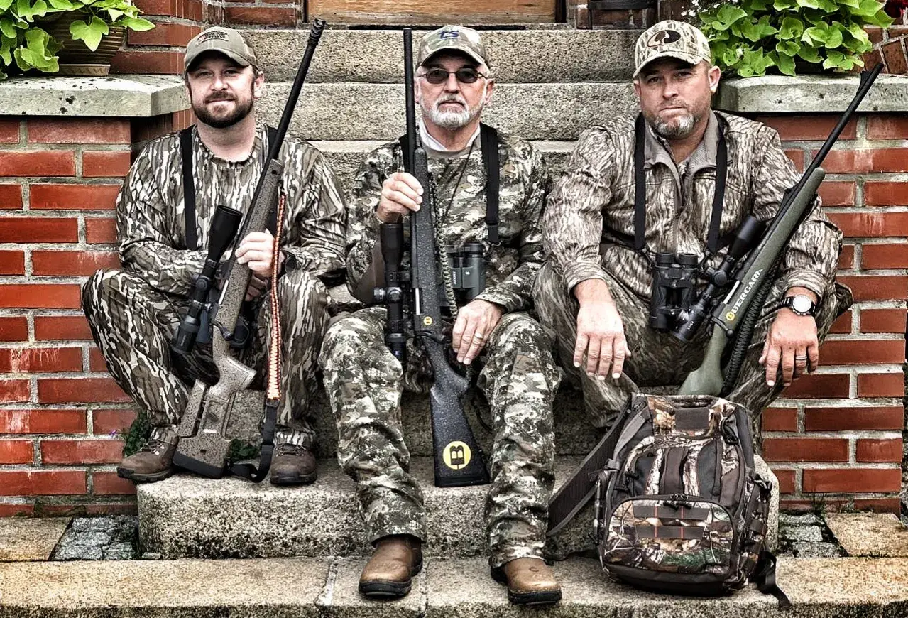 Trois chasseurs en tenue de camouflage, prêts pour traquer le cerf avec leurs fusils, dont un calibre 30 06.
