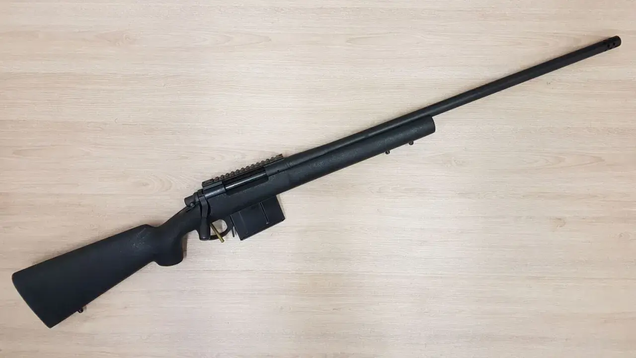 Fusil noir Remington 700 Police, prêt pour l'action sur fond de bois clair.