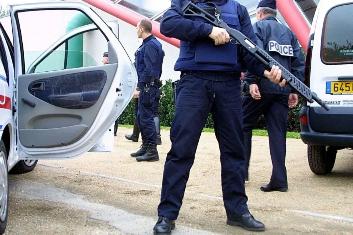 Un policier national tient un fusil à pompe, prêt à intervenir.