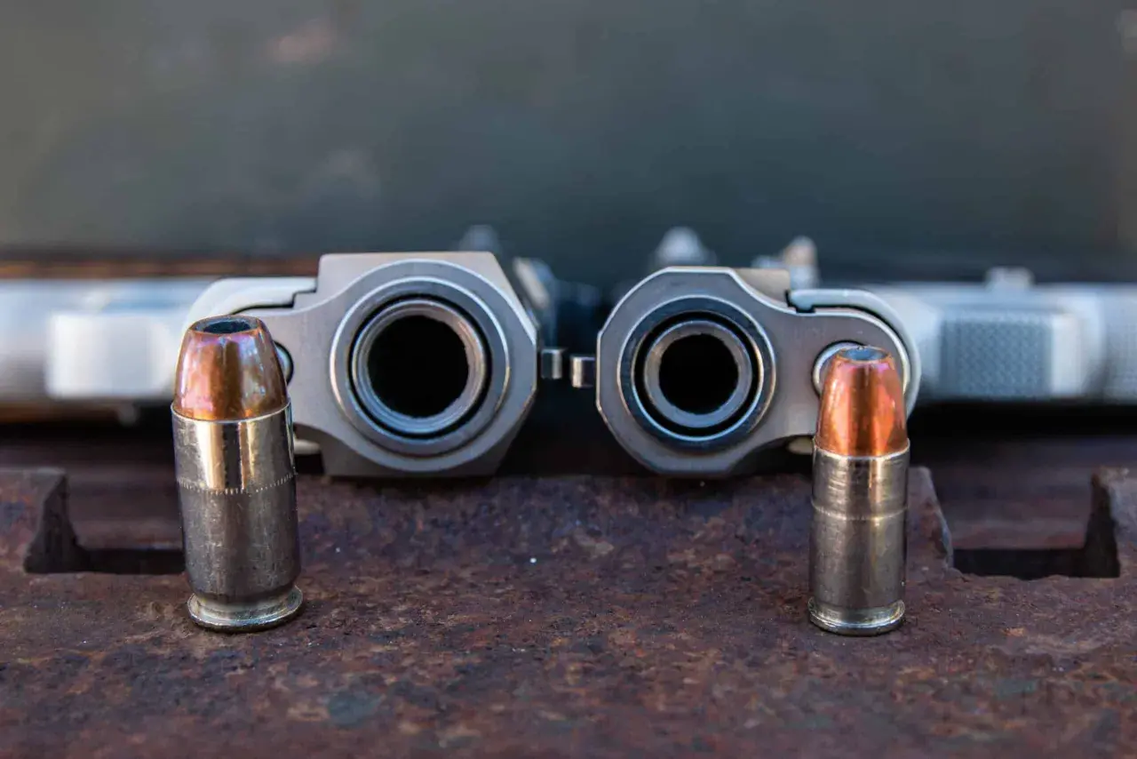 Deux canons de pistolets, un calibre 45 et un 9mm, se font face, chacun flanqué d'une balle.