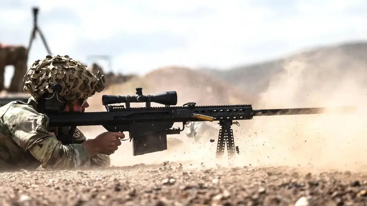 Un soldat tire avec un Barrett 50 munition, une douille s'&eacute;jecte dans un nuage de poussi&egrave;re.
