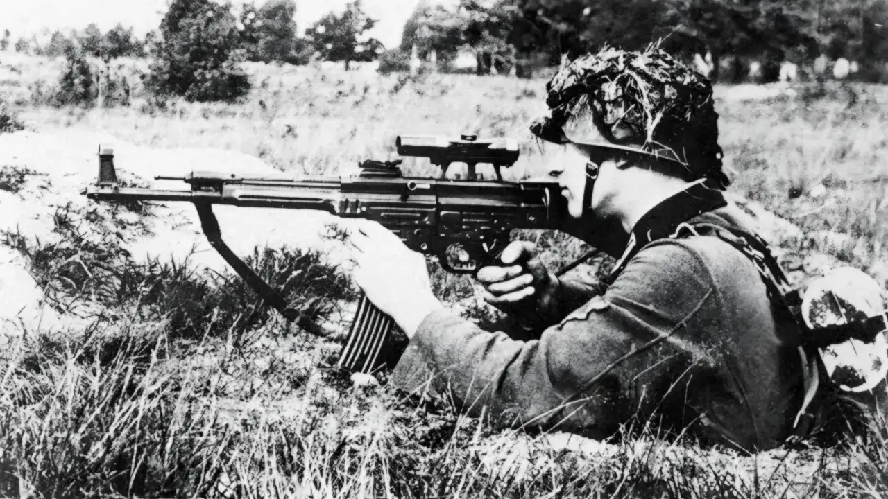 Soldat allemand en position couch&eacute;e, visant avec un fusil d'assaut allemand, camouflage sur le casque.
