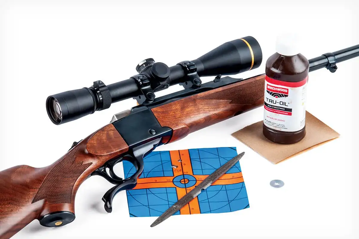 Un fusil Ruger N&deg;1 avec lunette, une cible, une lime et une bouteille de Tru-Oil.