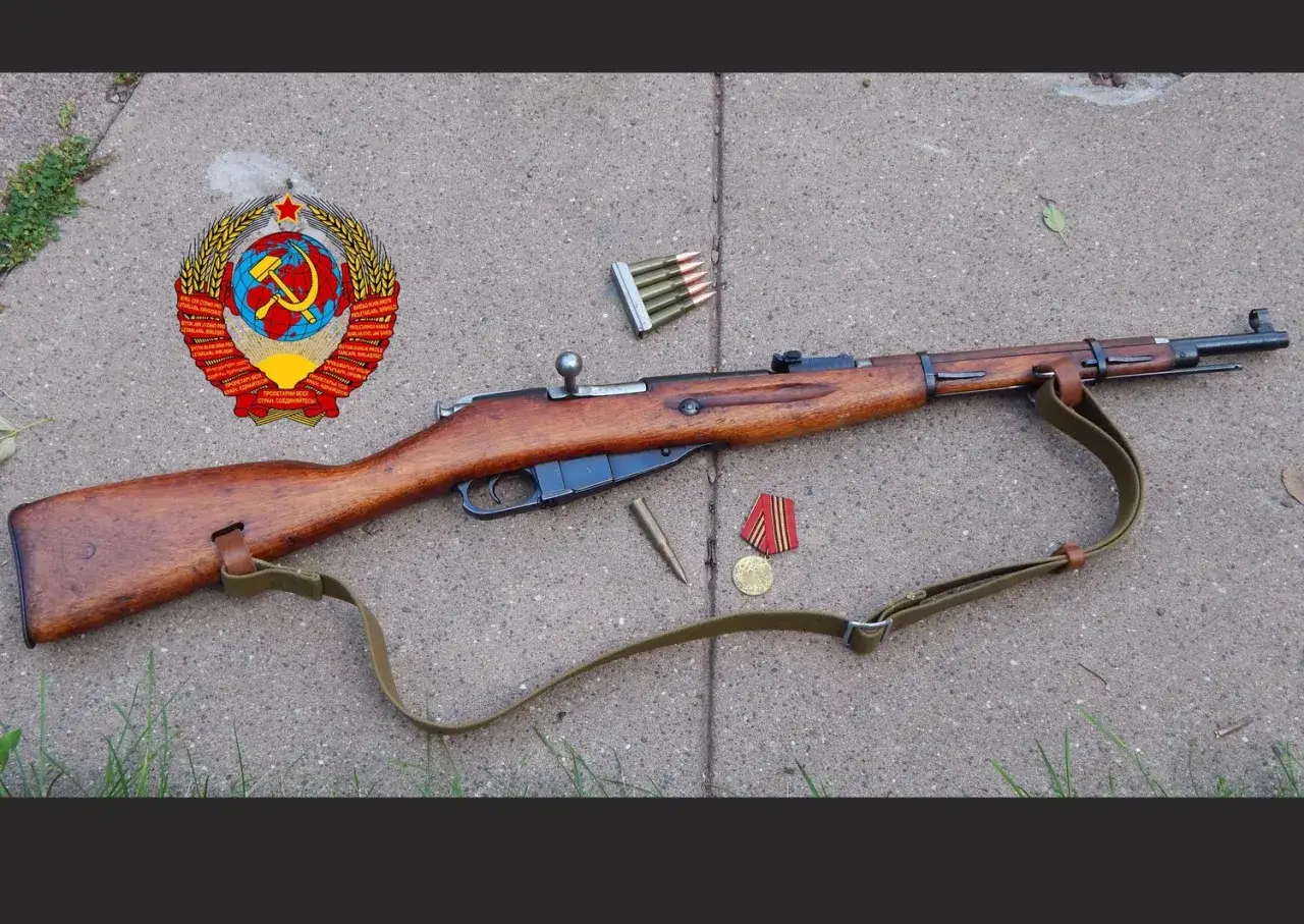 Un fusil Mosin-Nagant, un clip de munitions, une balle, et des médailles soviétiques sur un trottoir.
