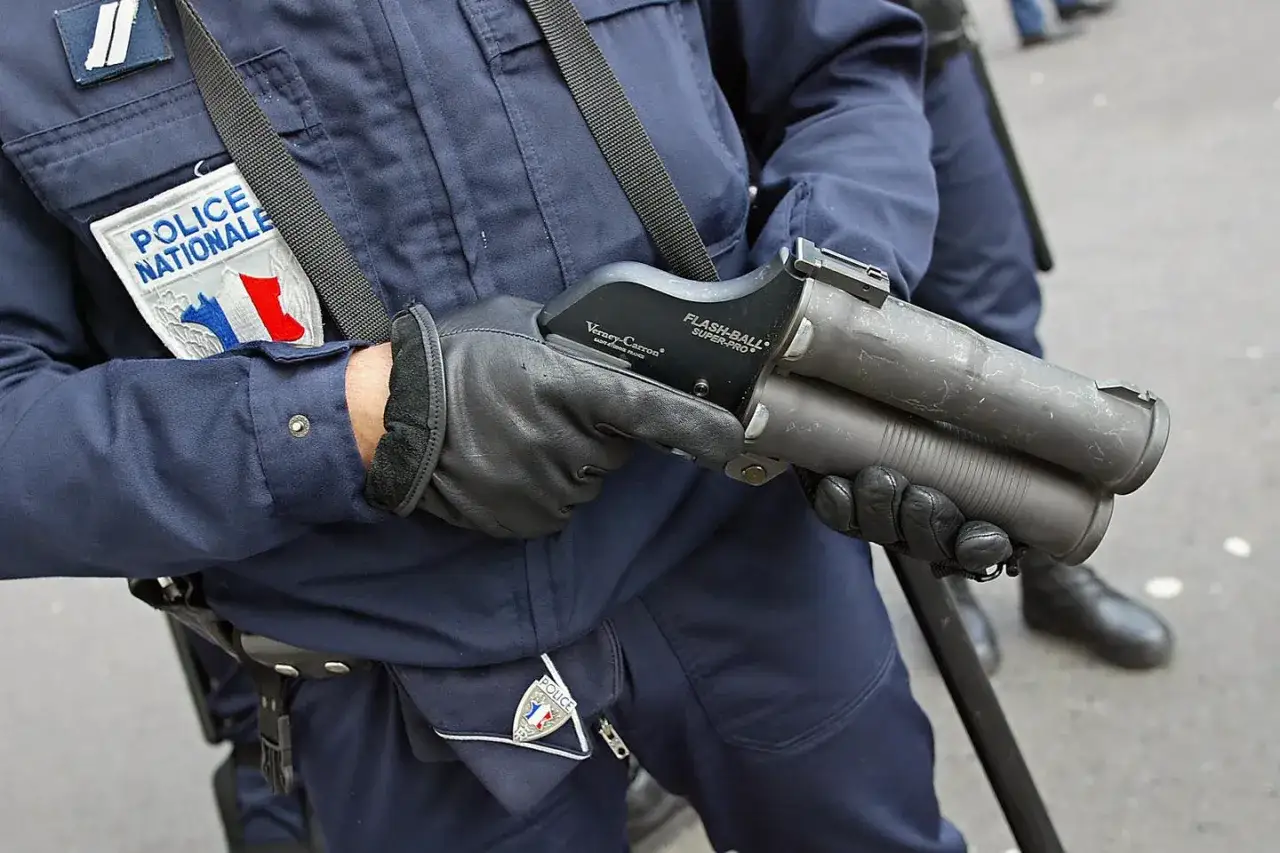 Un policier de la Police Nationale tient un lanceur Flash-Ball Super-Pro, arme de maintien de l'ordre.