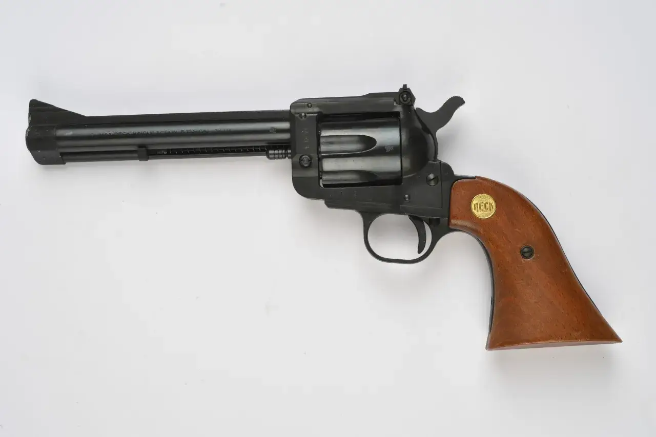 Revolver noir à 1 coup, calibre 22 LR, avec poignée en bois. Un objet qui soulève des questions sur la législation des armes.
