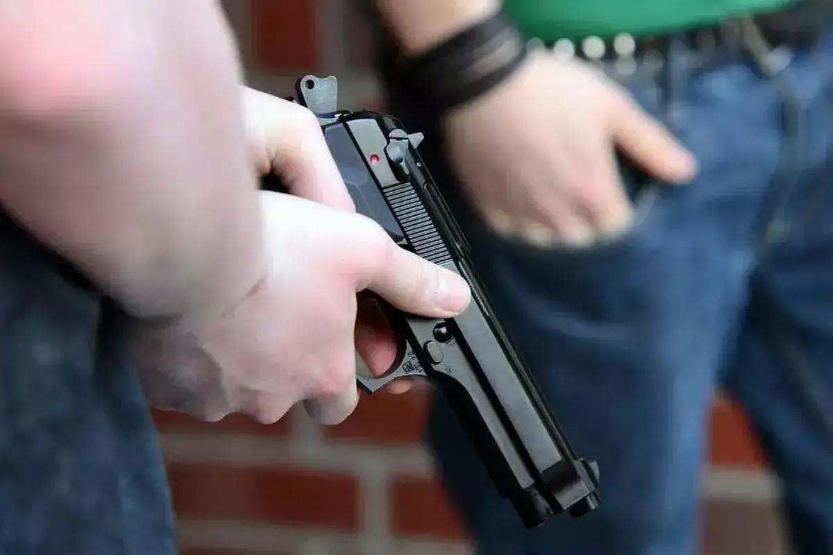 Main d'une personne tenant un pistolet &agrave; bille interdit, pr&ecirc;t &agrave; l'action.