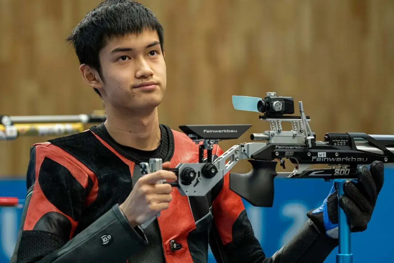 Jeune athlète concentré, prêt pour le tir sportif avec sa carabine air comprimé Feinwerkbau.