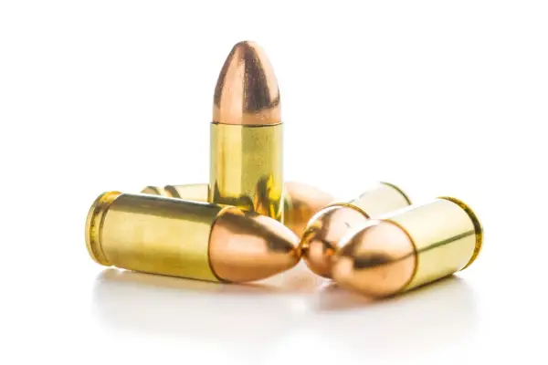 Un groupe de balles 9mm rip, leurs douilles dorées et leurs pointes cuivrées brillent sur fond blanc.