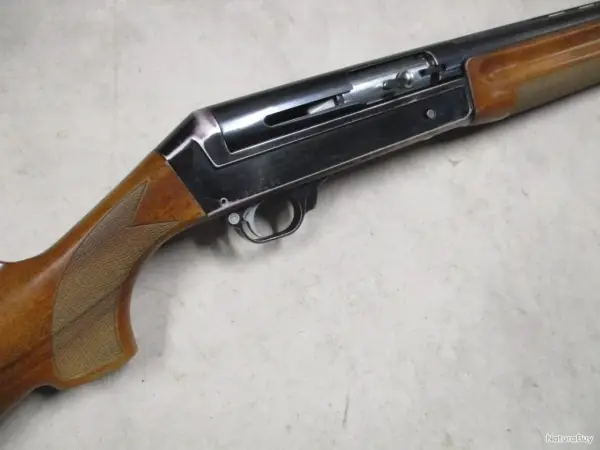 Le fusil de chasse Benelli 121, avec sa crosse en bois et son mécanisme apparent, prêt pour l'action.
